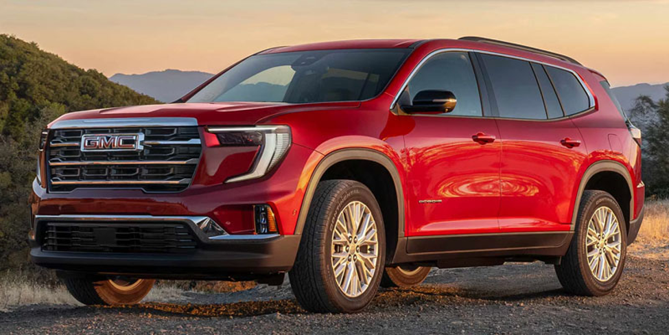 Red 2026 GMC Acadia sit on top of mountains with a sunset in the background